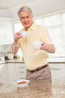 Senior man offering cup to camera