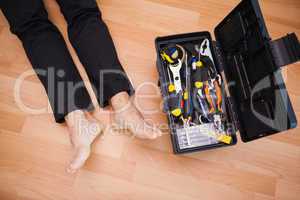 Handyman lying barefoot on floor with DIY tools