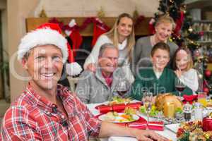 Smiling father in santa hat posing in front of his family