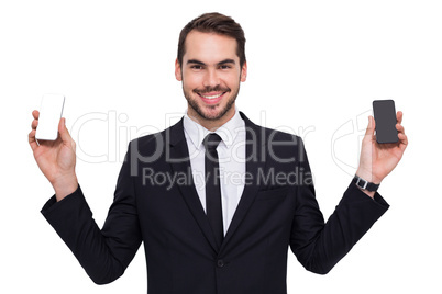 Smiling businessman holding mobile in each hand