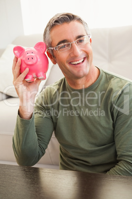 Smiling man posing with a piggy bank