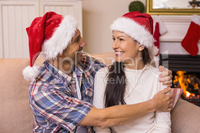 Festive couple in santa hat hugging on the couch