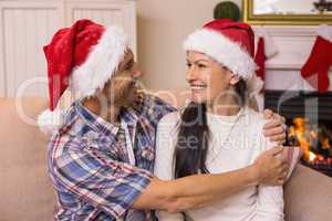 Festive couple in santa hat hugging on the couch
