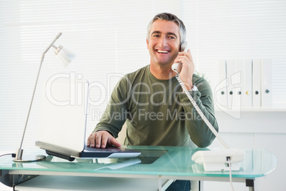 Smiling man on the phone using laptop