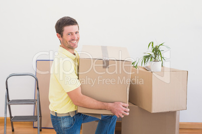 Smiling man carrying cardboard moving boxes at home
