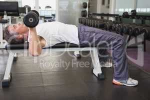 Fit man lifting dumbbells lying on the bench