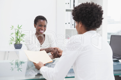 Smiling coworkers sitting and shaking hands