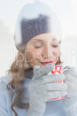 Pretty redhead in warm clothing holding mug