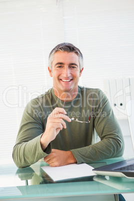 Smiling casual man holding his glasses