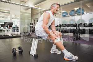 Injured man gripping his knee in the weights room