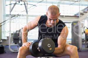 Young man exercising with dumbbell in gym