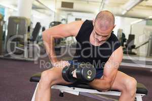 Young man exercising with dumbbell in gym