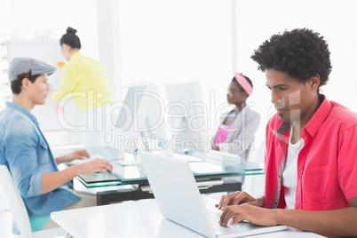 Young creative man using laptop at desk