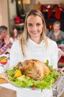 Portrait of a smiling woman showing the roast turkey