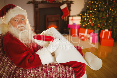 Smiling santa claus writing his list on scroll