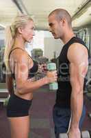 Couple exercising with dumbbells in gym