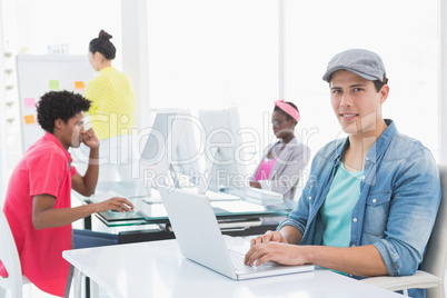 Young creative man using laptop at desk