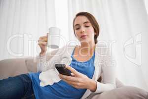 Pretty brunette sending a text on couch