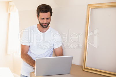 Happy man using laptop surrounded by boxes