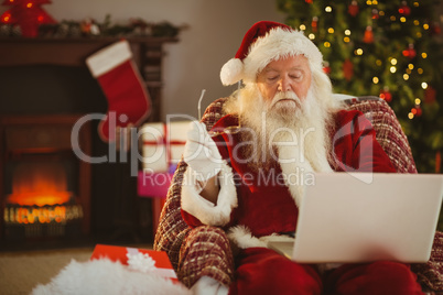 Santa claus using laptop on the armchair