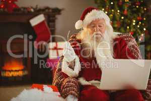 Santa claus using laptop on the armchair