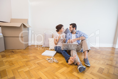 Cute couple sitting on floor using laptop