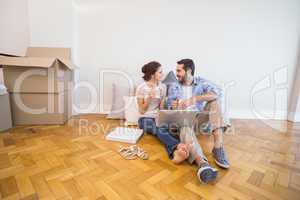 Cute couple sitting on floor using laptop