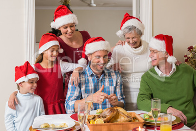 Happy extended family in santa hat at christmas dinner