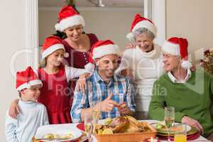 Happy extended family in santa hat at christmas dinner