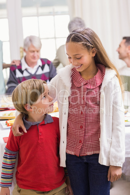 Brother and sister smiling at camera in front of their family