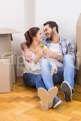 Cute couple toasting with champagne on floor