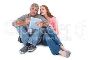Casual couple sitting using tablet