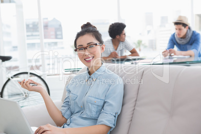 Young creative woman using laptop on couch