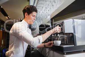 Smiling young barista making cup of coffee