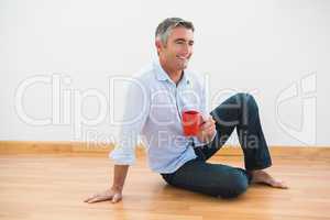 Smiling man sitting with a mug and barefoot