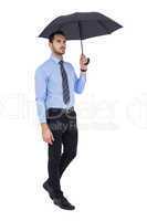 Serious businessman standing under umbrella
