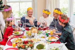 Grandfather in party hat carving chicken during dinner