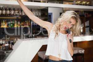 Blonde woman singing and dancing with hand up