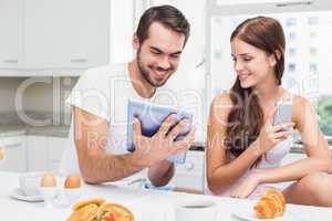 Young couple using tablet at breakfast