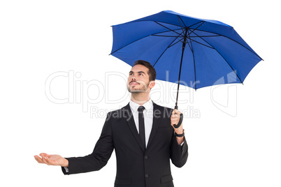 Cheerful businessman holding umbrella with hand out