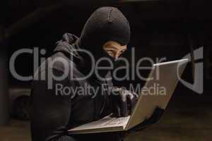 Focused burglar standing holding laptop