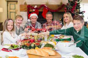 Smiling family pulling christmas crackers at the dinner table