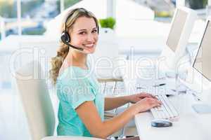 Pretty call centre agent sitting at her desk on a call