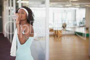 Fit woman drinking water in fitness studio