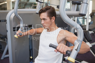 Fit man using weights machine for arms