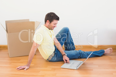 Casual man sitting on floor using laptop at home