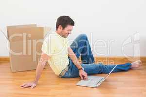 Casual man sitting on floor using laptop at home