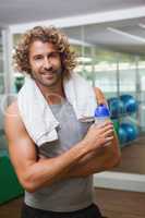 Smiling handsome man holding water bottle at gym