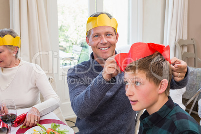 Smiling father putting party hat on sons head