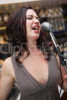 Cheerful pretty brunette singing with her microphone